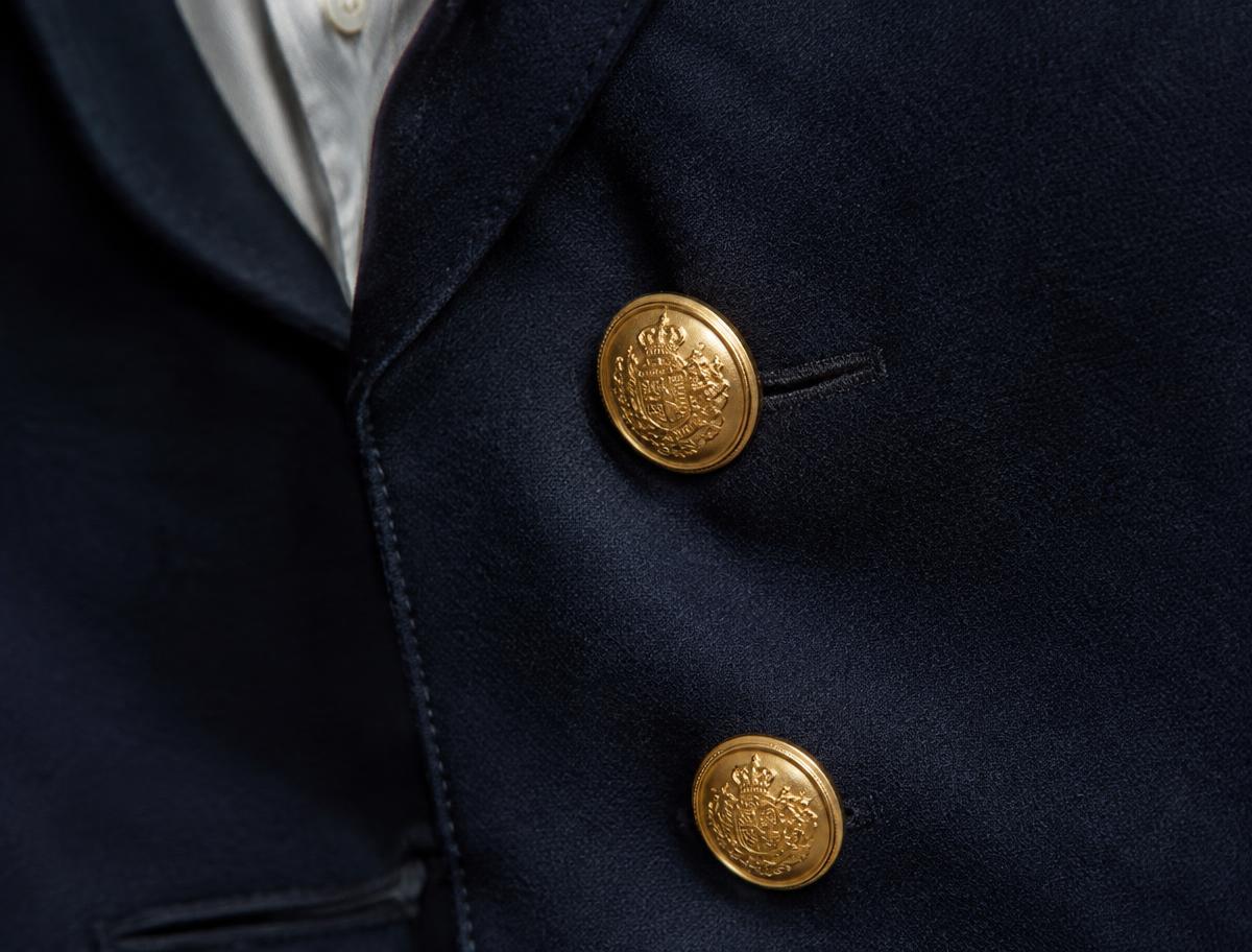 Close-up of polished brass buttons on a navy wool blazer