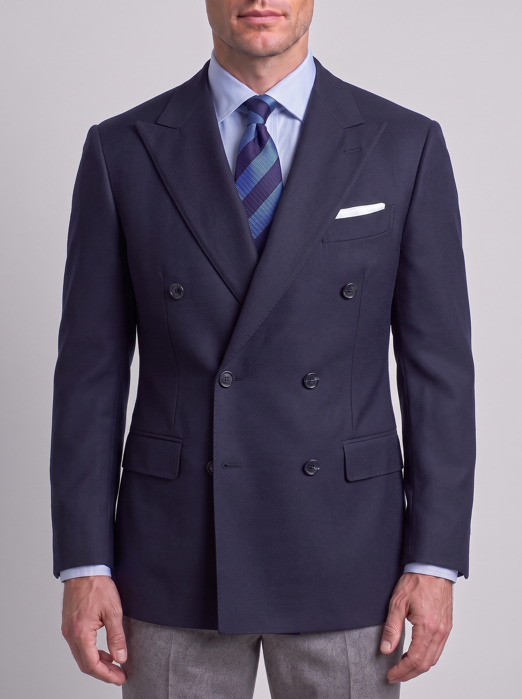 Man in a midnight navy twill double-breasted blazer with dark horn buttons on a grey studio backdrop