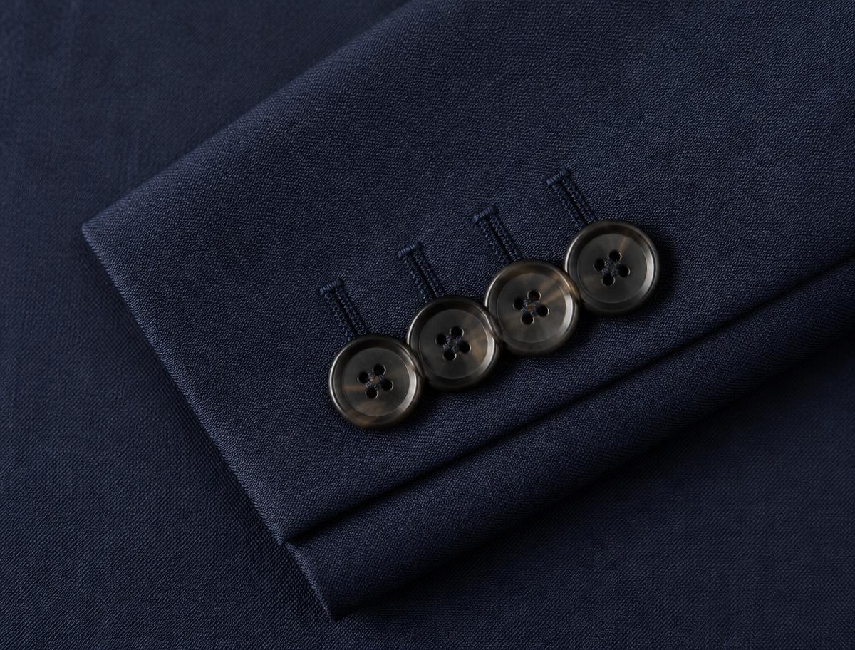 Close-up of horn buttons and a hand-sewn buttonhole on a navy suit jacket