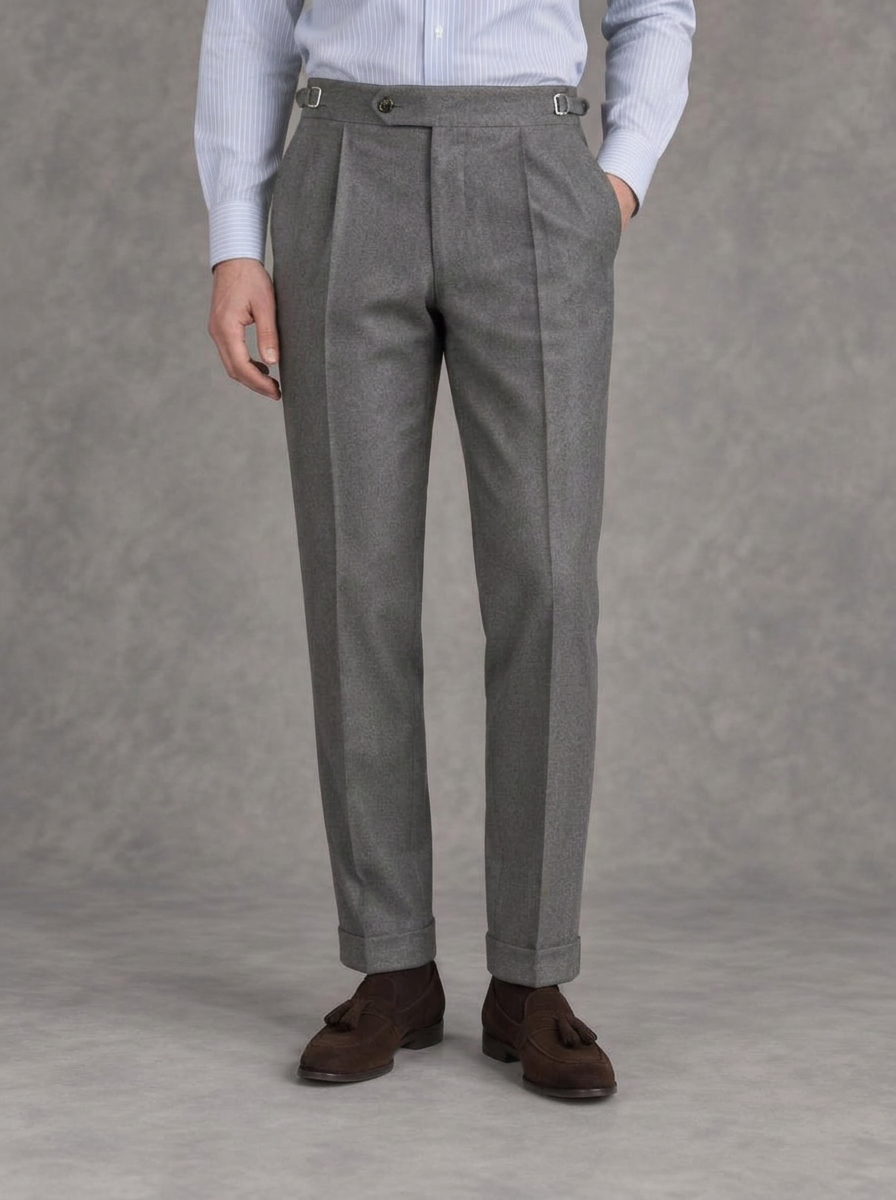 Grey single-pleat flannel trousers with side adjusters and turn-ups, worn with a striped blue shirt and brown suede tassel loafers