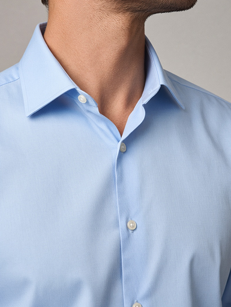 Close-up of a man wearing a fine light-blue shirt with a clean spread collar